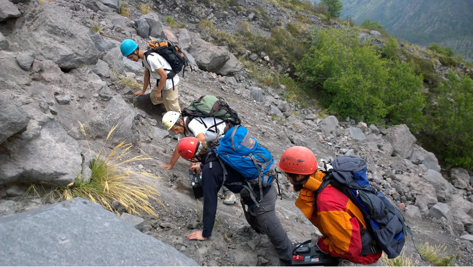 A team of scientists carrying research apparatus up a volcano in Mexico